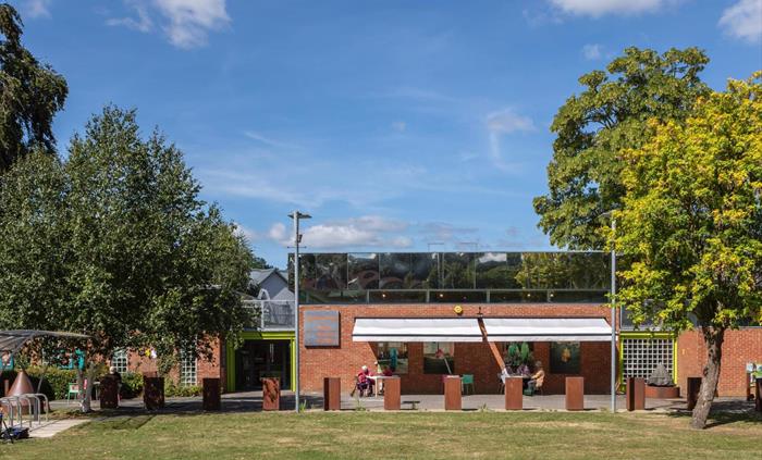 Brick Single Storey Building With reflective Mirror Panels on the top third of the walls. Reflecting the trees around the gallery